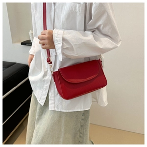 Close-up of red pebbled leather crossbody bag with adjustable strap and gold hardware