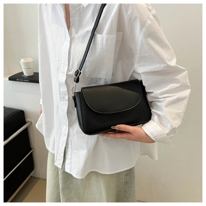 Close-up of minimalist black crossbody bag showing its smooth texture and adjustable strap