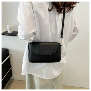 Minimalist black matte crossbody bag worn by a model in a modern lifestyle setting