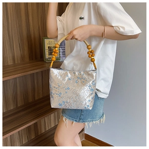 Detailed shot of silk texture handbag with floral patterns and natural wooden bead handle