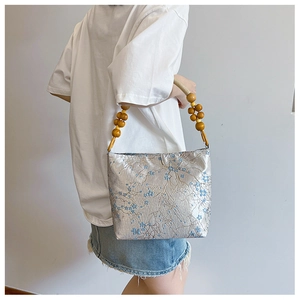 Detail of floral silk bucket bag with vintage wooden beads on the shoulder strap