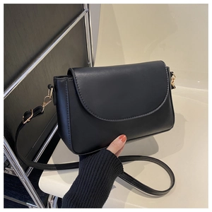 Detailed close-up of a black matte leather shoulder bag with gold metal hardware