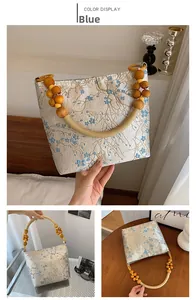 Detail of silk texture bucket bag with blue floral patterns and wooden bead handles