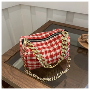 Sac à main vintage à carreaux rouges et blancs avec chaînes dorées sur table en bois