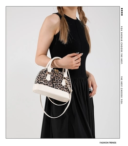 Detail of leopard print shell bag with beige leather trim and dual gold zippers