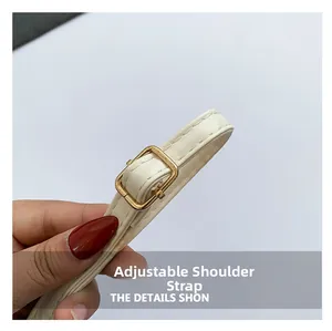 Close-up of the adjustable white leather shoulder strap with gold metal buckle detail