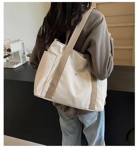 Detail view of the nylon tote bag with wide khaki strap and metal buckle in coffee shop