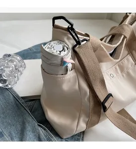 Detail view of the large side pocket on a beige canvas tote bag holding a long folding umbrella