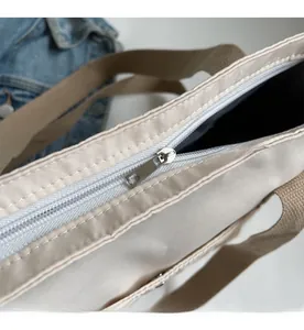 Macro view of smooth white zipper closure on beige nylon bag with khaki woven handle