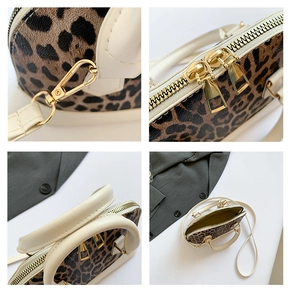 Close-up of leopard print shell bag featuring golden hardware and leather strap hooks