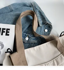 Detail of cream canvas tote bag with brown woven handle and sturdy black metal hooks