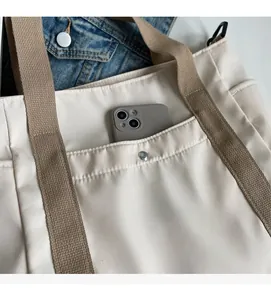 Detail of durable nylon tote featuring a functional front pocket with silver snap button