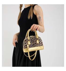 Detail of leopard print shell bag featuring metallic gold handles and dual zippers