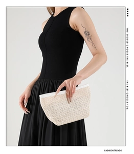 Modella con borsa a mano intrecciata beige con trama in paglia e chiusura a zip