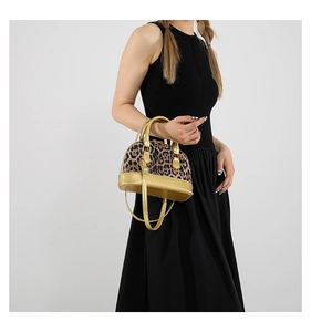 Leopard print shell handbag with golden adjustable strap worn by model on white background