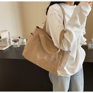 Dettaglio della tasca laterale di una borsa tote in tela kaki con ampia tracolla