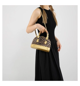 Detail of leopard print shell bag with metallic gold handles and textured fur material