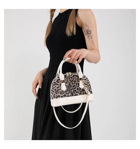 Detail of leopard print shell bag with cream trim and gold zipper for elegant styling