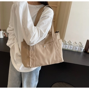 Dettaglio borsa tote kaki con tasca frontale e tracolla in tessuto sulla modella
