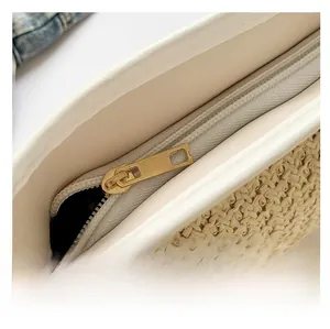 Dettaglio della borsa in paglia intrecciata con finiture in pelle bianca e zip dorata