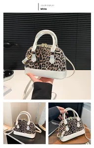 Detail of leopard print shell bag featuring white PU handles and gold metal hardware