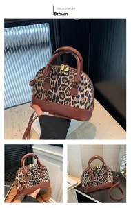 Detailed view of leopard print shell bag with brown leather handles and gold metal zippers