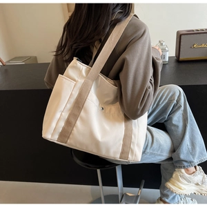 Dettaglio borsa tote in tela bianca con tracolla cachi e pratica tasca laterale