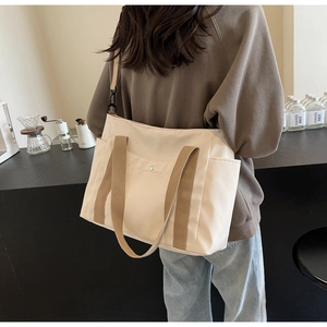 Dettaglio di una borsa tote in tela beige con manici marroni in un ambiente caffè