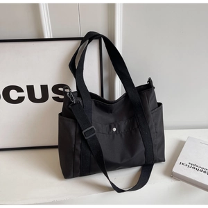 Dettaglio della borsa tote in nylon nero con tracolla regolabile e tasche laterali utili