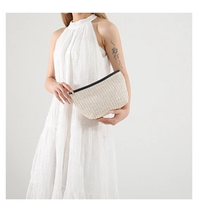 Dettaglio pochette in paglia intrecciata con cerniera nera per look estivo
