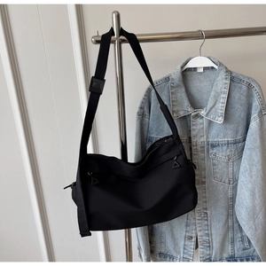 Detail of black waterproof nylon tote bag featuring adjustable wide strap and zip puller