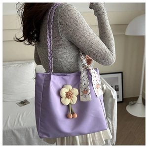 Detail view of purple canvas tote bag featuring 3D floral accent and woven rope handles