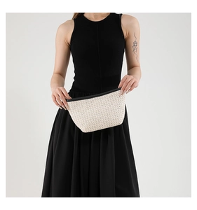 Dettaglio della pochette in paglia intrecciata con bordo nero e trama di lino