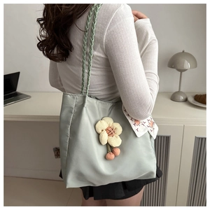 Detail of mint green tote bag with braided handles, 3D flower charm, and printed scarf