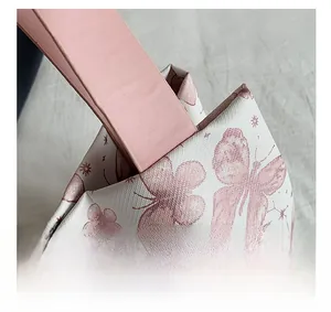 Détail de la poignée en similicuir rose et de l'imprimé papillon sur un sac fourre-tout