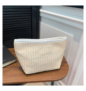 Dettaglio pochette in paglia intrecciata con finiture in pelle bianca su legno