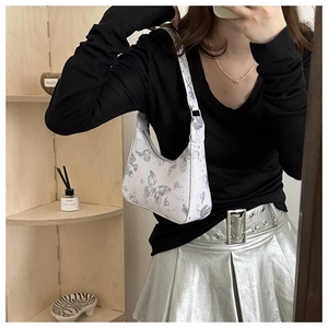 Mirror selfie showing a white underarm bag with blue butterfly print and silver zipper