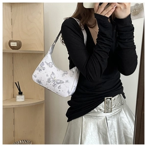 Detail of white underarm bag with butterfly print worn with a stylish black top