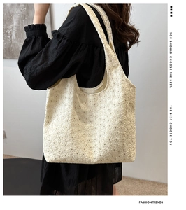 Detailed embroidery on cream floral tote bag held by model in black outfit