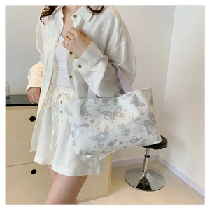 Détail du sac cabas blanc imprimé papillon avec bandoulière mauve sur un mannequin