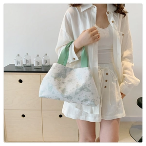 Détail du sac cabas en toile blanche avec imprimés papillons et poignées ruban vert