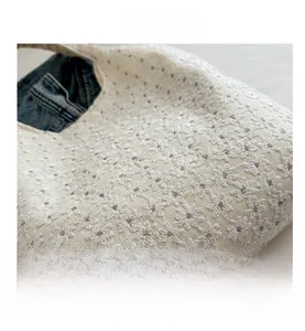 Detailed close-up of intricate white floral embroidery on cream canvas shoulder bag