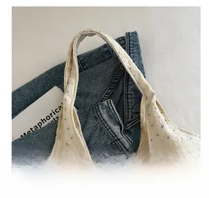 Detail shot of white daisy embroidery on cream canvas tote with a lifestyle background