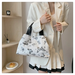Sac fourre-tout blanc à imprimé papillon porté par un mannequin dans un décor de bureau