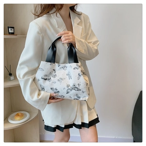 Détail du sac seau blanc avec motifs papillons noirs et anses contrastées élégantes