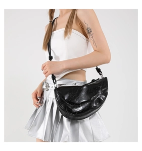 Close-up of black crescent shoulder bag with pleated leather texture and knotted strap detail