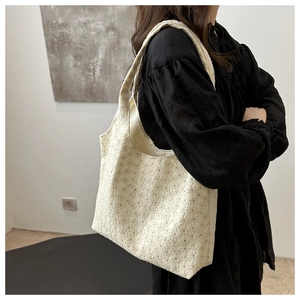 Detailed close-up of ivory tote bag with hollow floral embroidery on soft fabric