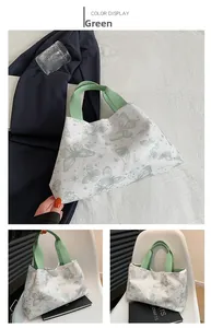 Détails d'un sac cabas vert à imprimé papillon avec des poignées contrastées
