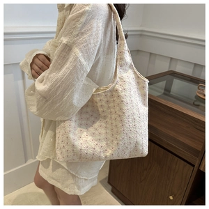 Detail of floral embroidery on a cream tote bag shown with model for size