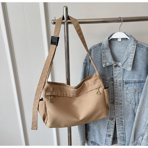 Detail of adjustable strap with black buckle and vertical zippers on khaki tote bag